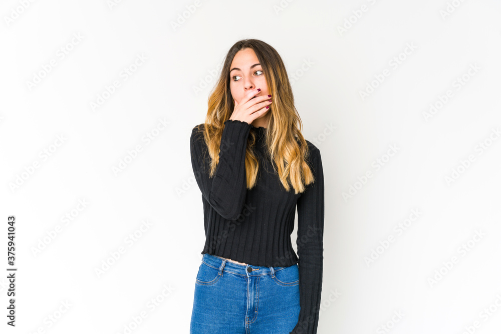 Young caucasian woman isolated on white background thoughtful looking to a copy space covering mouth with hand. Young caucasian woman isolated on white background thoughtful looking to a copy space covering mouth with hand.