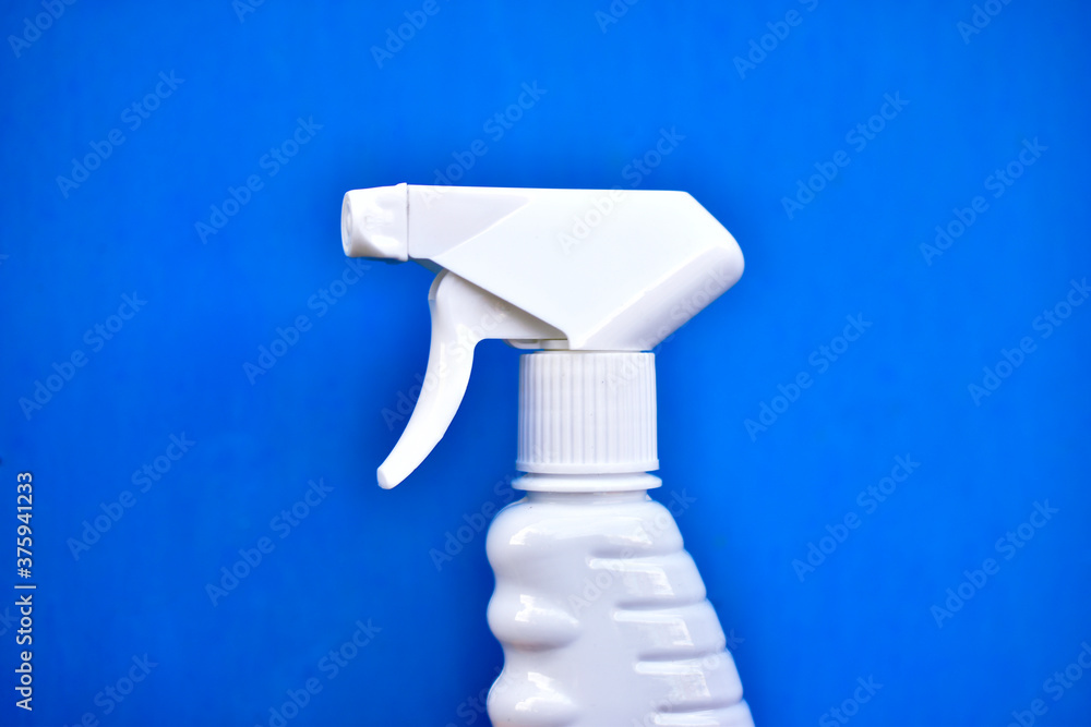 Plastic container with a spray gun in hand on a blue background Plastic container with a spray gun in hand on a blue background