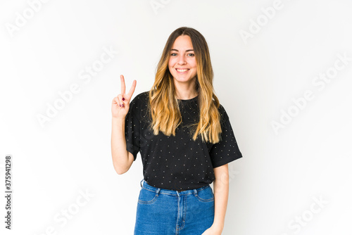 Young caucasian woman isolated on white background joyful and carefree showing a peace symbol with fingers.