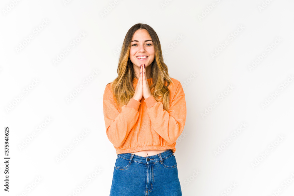 Young caucasian woman isolated on white background holding hands in pray near mouth, feels confident. Young caucasian woman isolated on white background holding hands in pray near mouth, feels confident.