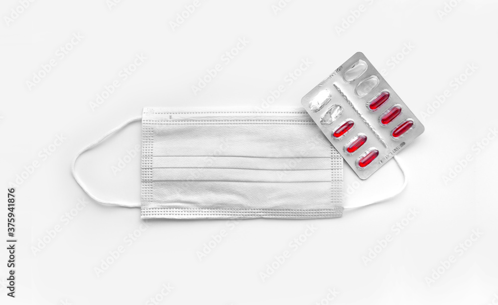 Medical mask and pills. Protection from coronavirus. Covid19 protection concept with pharmaceutical tablets in capsules near a mask. Medical mask and pills. Protection from coronavirus. Covid19 protection concept with pharmaceutical tablets in capsules near a mask.