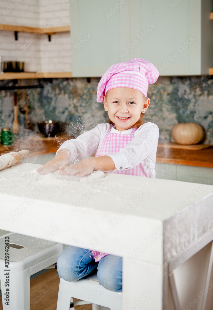 little girl in the kitchen kneads dough and sprinkled flour little girl in the kitchen kneads dough and sprinkled flour