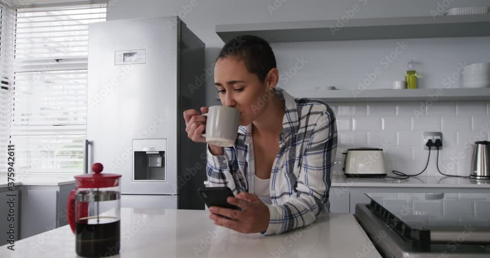 Woman using smartphone and having a coffee in kitchen Woman using smartphone and having a coffee in kitchen