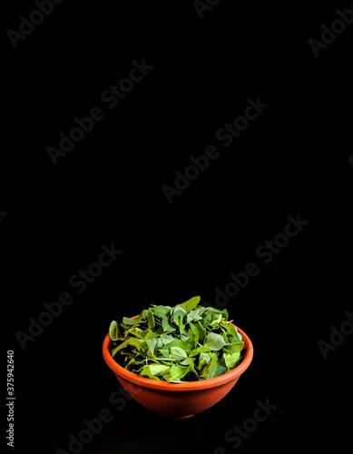 Chipilin leaves on a clay bowl with black background. typical food of Guatemala