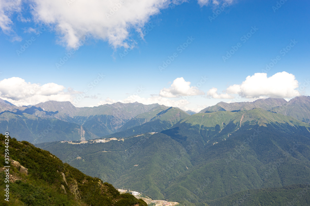Fototapeta premium Magnificent panoramic view the coniferous forest on the mighty Mountains and beautiful blue sky background. Beauty of wild virgin Russian nature. Peacefulness.