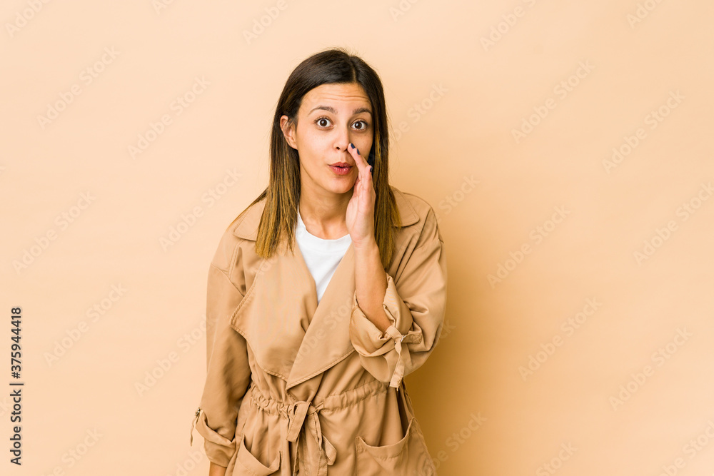 Young woman isolated on beige background is saying a secret hot braking news and looking aside Young woman isolated on beige background is saying a secret hot braking news and looking aside