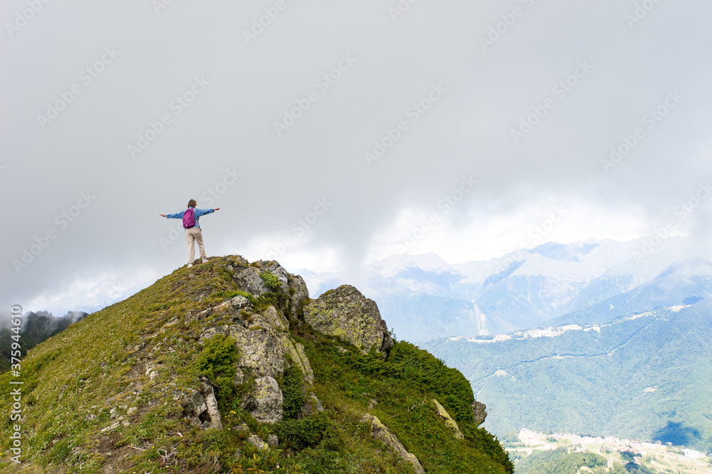 Young hiker stand in beautiful mountains on hiking trip. Active person resting outdoors in  nature. Backpacker camping outside recreation active