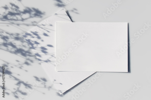 Mockup poster or flyer for presentation white sheets of paper with shadow of a plant on a gray background in a modern minimalist style. Congratulations blank, business card or invitation