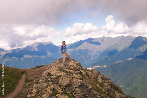 Young hiker stand in beautiful mountains on hiking trip. Active person resting outdoors in nature. Backpacker camping outside recreation active
