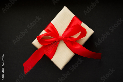 Gift with red bow in the center of the black background closeup