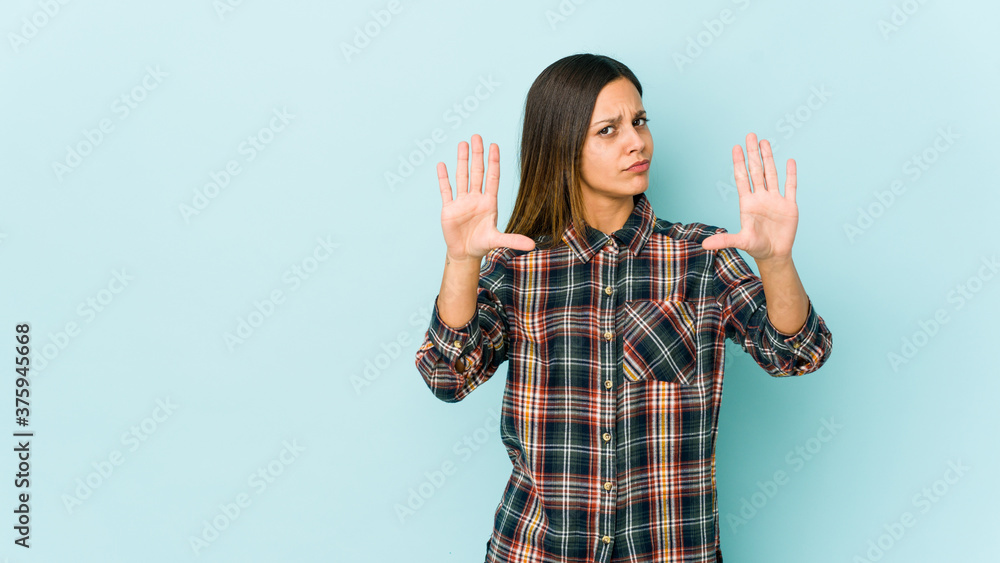 Young woman isolated on blue background standing with outstretched hand showing stop sign, preventing you. Young woman isolated on blue background standing with outstretched hand showing stop sign, preventing you.