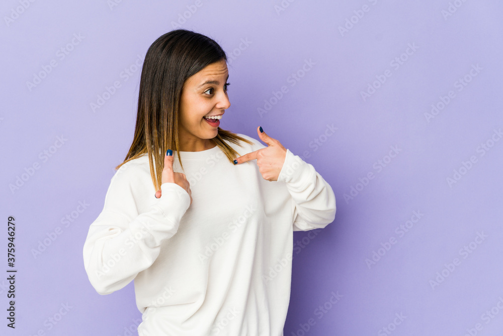 Young woman isolated on purple background surprised pointing with finger, smiling broadly. Young woman isolated on purple background surprised pointing with finger, smiling broadly.
