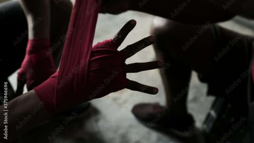 Mid section of Coach tying hand wrap to a Boxer in the gym Mid section of Coach tying hand wrap to a Boxer in the gym