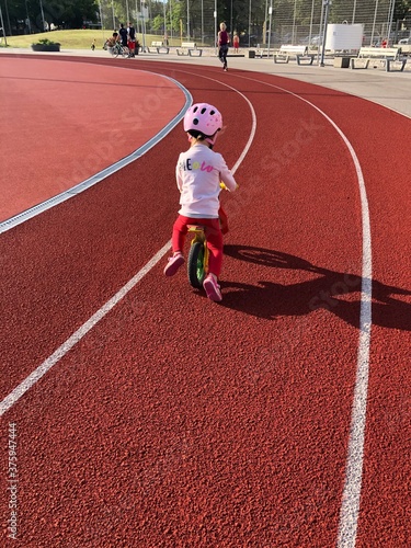 little girl riding her balance bicycle on running track in a stadium