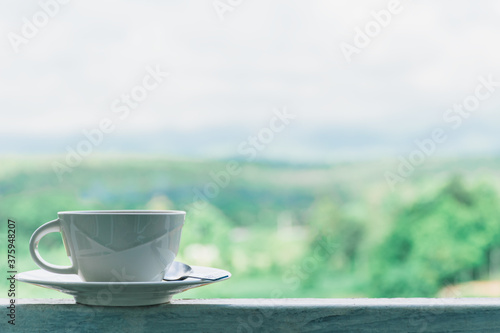 Coffee​ or tea​ cup​ blue color​ on the back porch, blurred background of the mountain view and green forest, Countryside of .Changmai Thailand, Cozy atmosphere is suitable for relaxing on vacation.