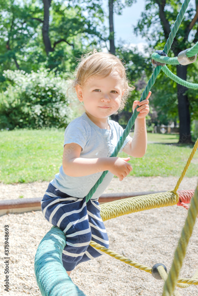 Cute little child having fun playing in the park, beautiful summer sunny day in children playground Cute little child having fun playing in the park, beautiful summer sunny day in children playground