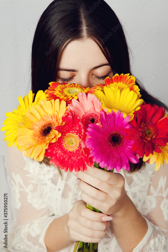 Beautiful woman in white dress hid her face behind large bouquet of colorful bright gerberas. Beautiful woman in white dress hid her face behind large bouquet of colorful bright gerberas.