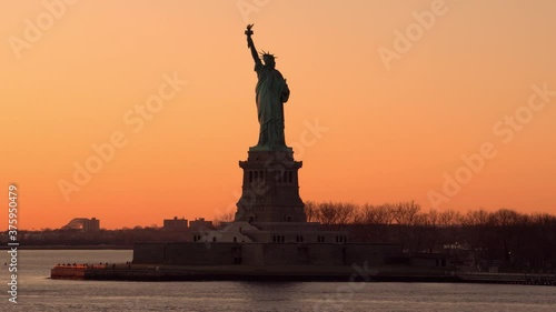 Lady liberty with the red orange sunset sky in the background.