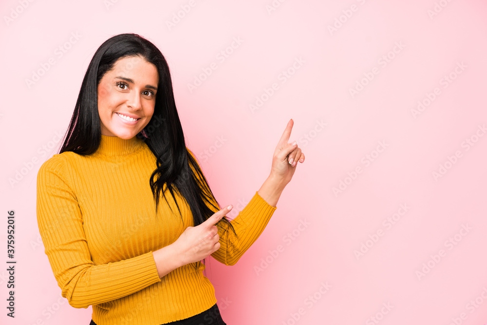 Young caucasian woman isolated on a pink background shocked pointing with index fingers to a copy space. Young caucasian woman isolated on a pink background shocked pointing with index fingers to a copy space.