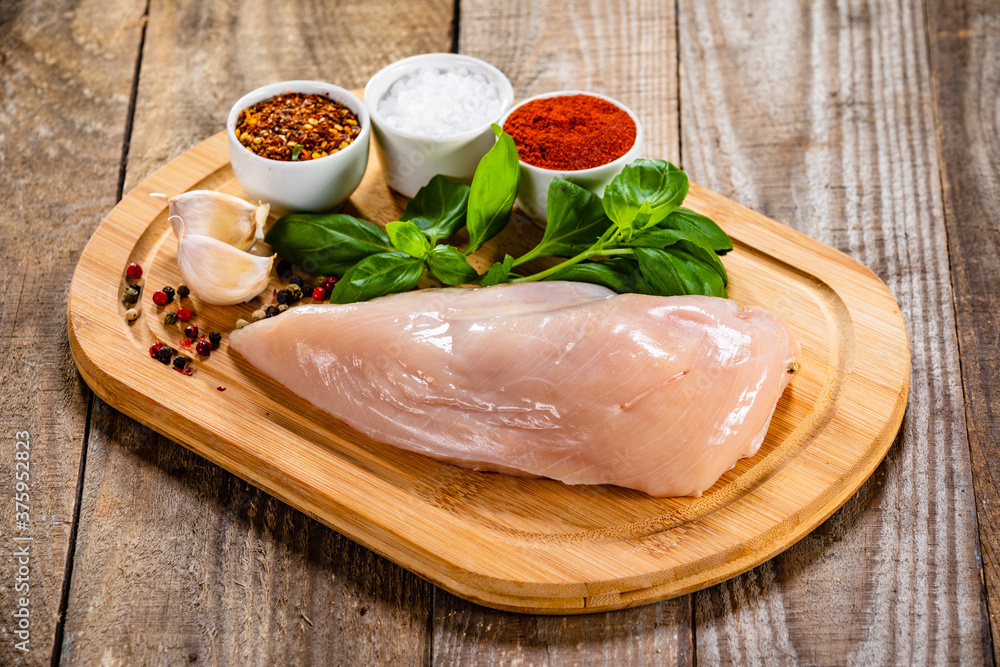 Fresh raw chicken fillet on wooden cutting board on wooden table Fresh raw chicken fillet on wooden cutting board on wooden table