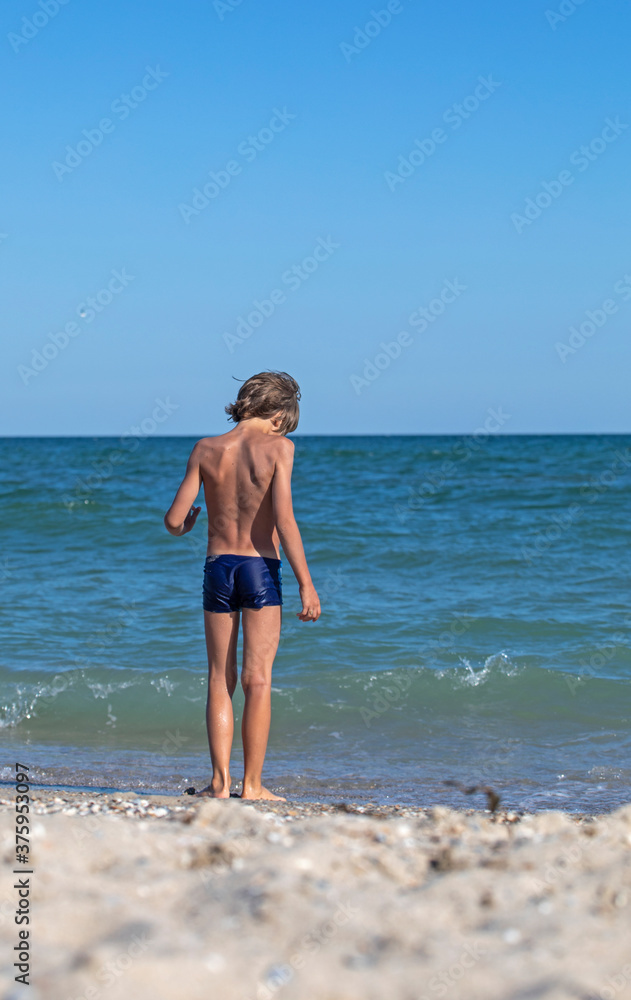 happy boy walks into the sea, vertical format happy boy walks into the sea, vertical format