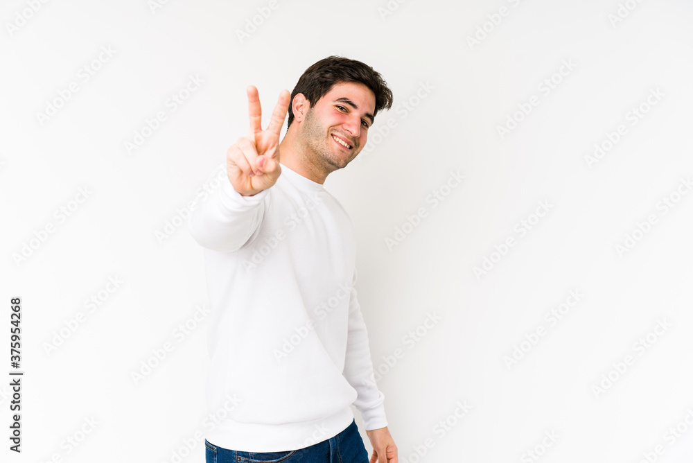 Young man isolated on white background joyful and carefree showing a peace symbol with fingers. Young man isolated on white background joyful and carefree showing a peace symbol with fingers.