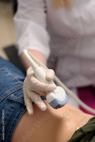 Medical ultrasound equipment in the clinic.
Close-up of a scanner covered with ultrasound gel in the doctor's hands. Health and beauty concept.