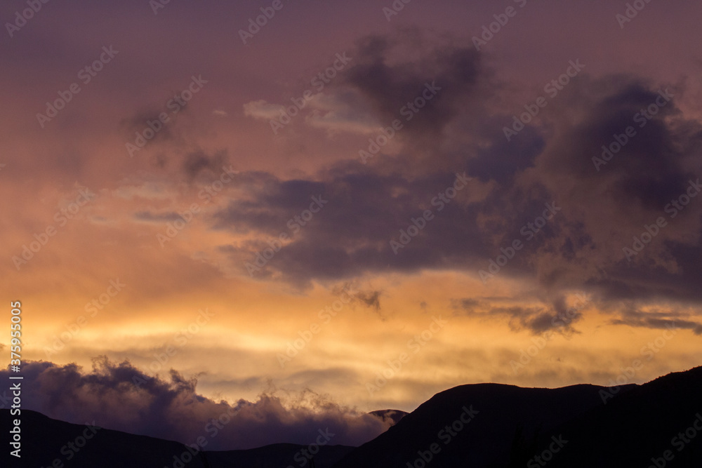 Enchanting sunset. View of the mountains silhouette at nightfall. Beautiful dusk colors in the sky and clouds.