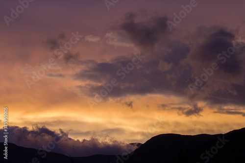 Enchanting sunset. View of the mountains silhouette at nightfall. Beautiful dusk colors in the sky and clouds.