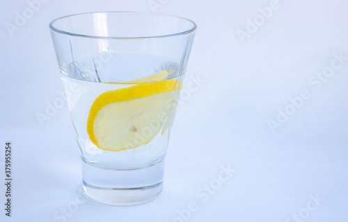 A glass of water with a slice of lemon close-up on a white background. Isolated. Space for your text