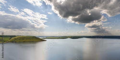 Beautiful panoramic view of a large lake among the hills on a sunny day. River and rocks landscape. Lake Bakota and the Dniester River. Summer vacation camping and tourist destinations in Ukraine.