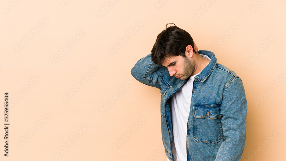 Young man isolated on beige background having a neck pain due to stress, massaging and touching it with hand. Young man isolated on beige background having a neck pain due to stress, massaging and touching it with hand.