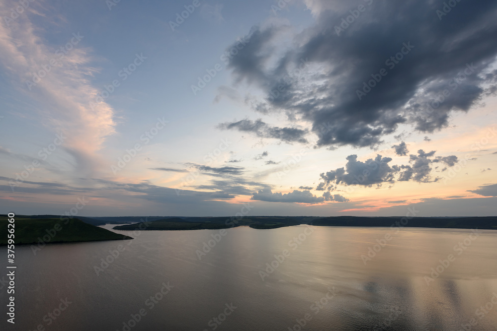 Beautiful sky at dusk over a large lake among the hills. Lake Bakota and the Dniester River. Summer camping and tourist destinations in Ukraine.
