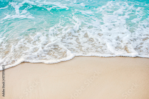 Foamy waves on a sandy beach with blue sea water at a tropical beach