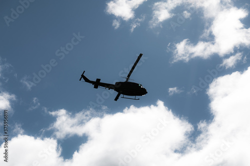 silhouette of a (black) helicopter flying in front of dramatic sky 