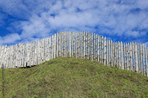 Fototapeta Sharp protective palisade on the earthen rampart of the old fortress