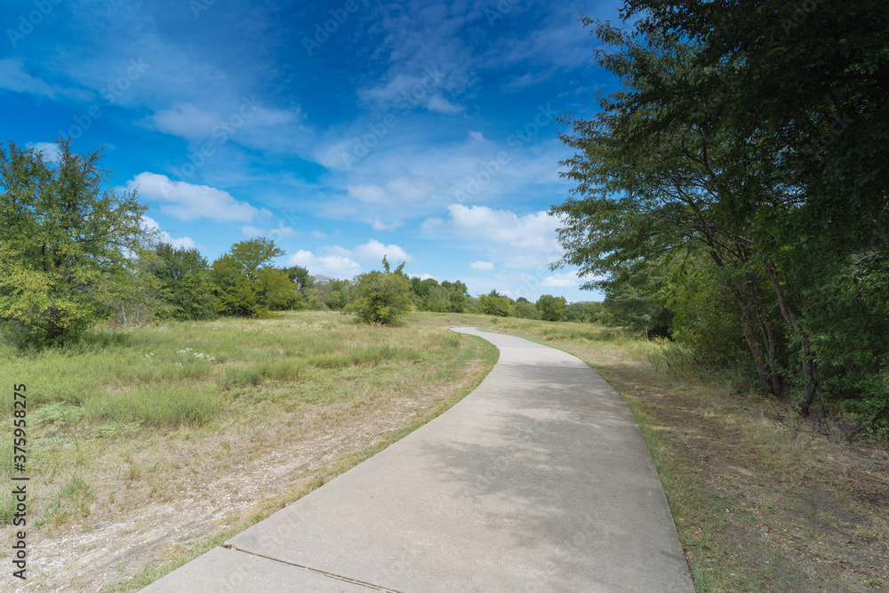 A concrete path in a Texas urban nature reserve on a sunny September day. A concrete path in a Texas urban nature reserve on a sunny September day.