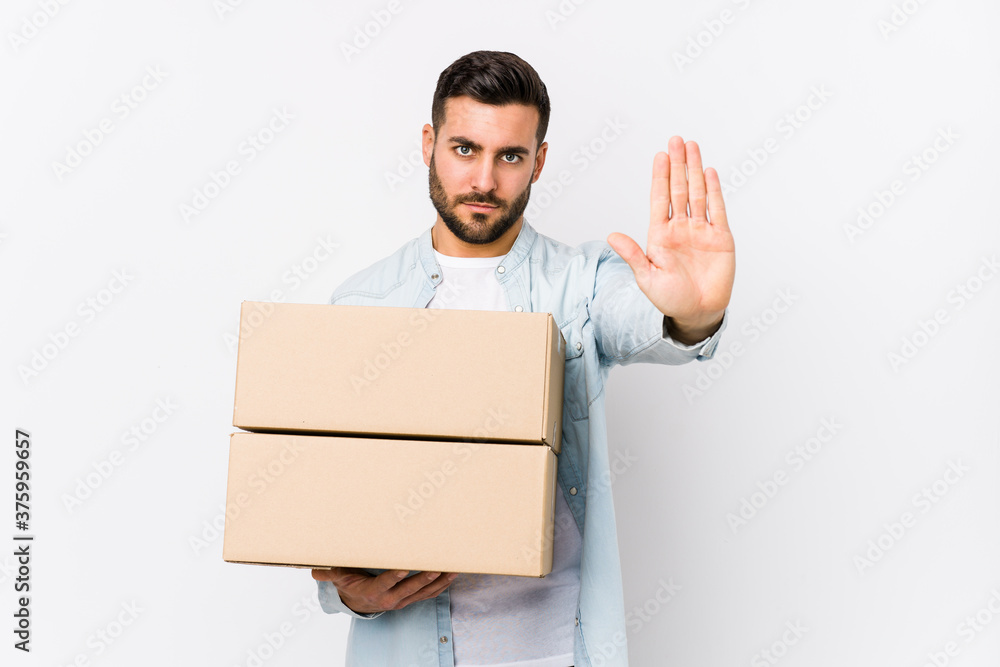 Young caucasian man moving to a new home isolated standing with outstretched hand showing stop sign, preventing you. Young caucasian man moving to a new home isolated standing with outstretched hand showing stop sign, preventing you.