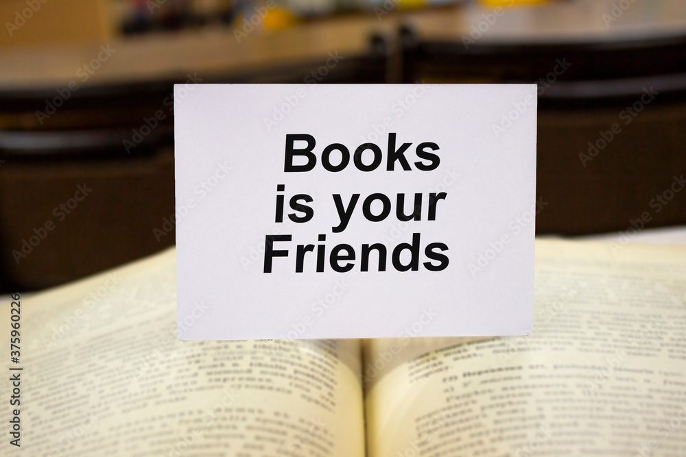 Books is youe friends written in white note on open book Books is youe friends written in white note on open book
