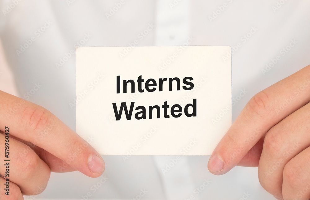 Man's hands take a card with words Interns Wanted, finance and business concept. Man's hands take a card with words Interns Wanted, finance and business concept.
