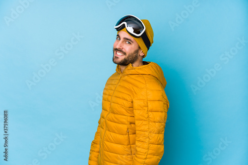 Young skier caucasian man isolated looks aside smiling, cheerful and pleasant. © Asier