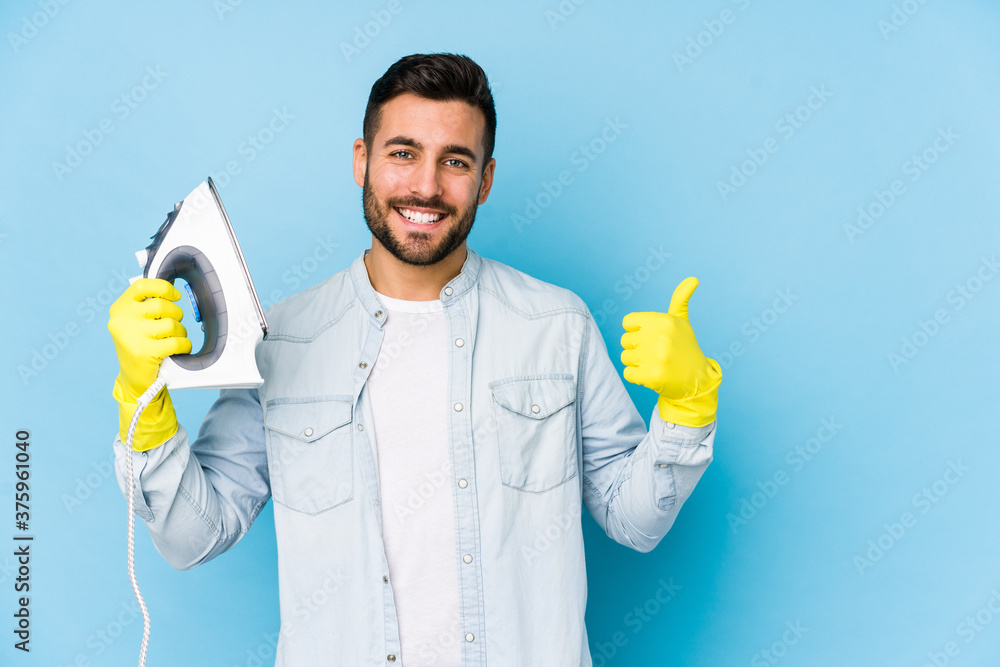 Portrait of young man ironing isolated smiling and raising thumb up Portrait of young man ironing isolated smiling and raising thumb up