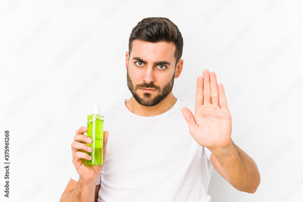 Young caucasian man holding a moisturizer with aloe vera isolated standing with outstretched hand showing stop sign, preventing you. Young caucasian man holding a moisturizer with aloe vera isolated standing with outstretched hand showing stop sign, preventing you.