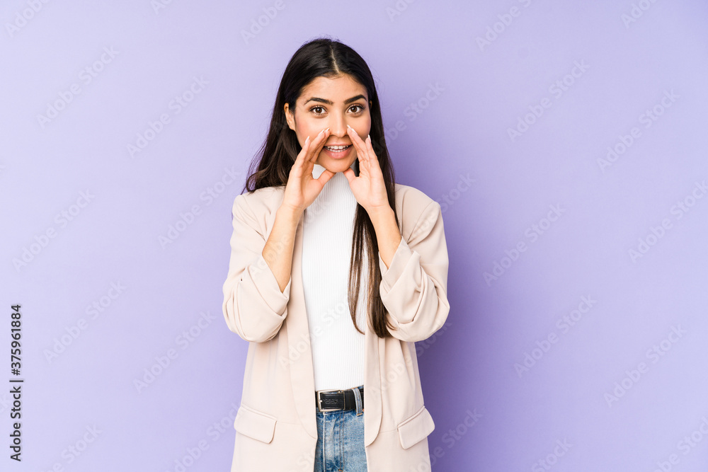 Young indian woman isolated on purple background saying a gossip, pointing to side reporting something. Young indian woman isolated on purple background saying a gossip, pointing to side reporting something.