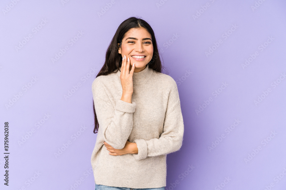 Young indian woman isolated on purple background laughs happily and has fun keeping hands on stomach. Young indian woman isolated on purple background laughs happily and has fun keeping hands on stomach.