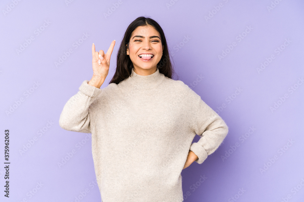 Young indian woman isolated on purple background showing rock gesture with fingers Young indian woman isolated on purple background showing rock gesture with fingers