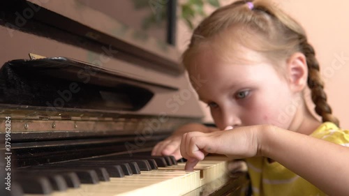 The child is tired of learning a music lesson. A pretty girl put her head on the piano keys. A little girl plays the piano in a music class.4k