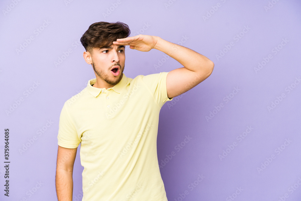 Young arabian man isolated on a purple background looking far away keeping hand on forehead. Young arabian man isolated on a purple background looking far away keeping hand on forehead.