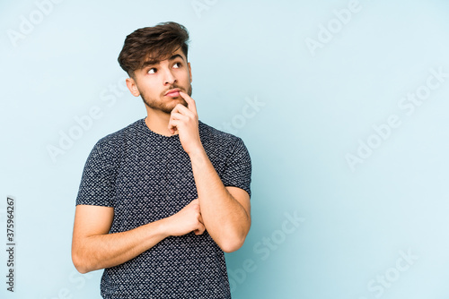 Photos Young arabian man isolated on a blue background looking sideways with doubtful and skeptical expression