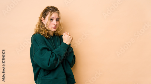 Young caucasian woman isolated on beige background scared and afraid. © Asier